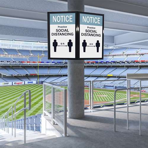 Stadium concourse photograph showing two portrait signage displays mounted back to back on a round column using Chief column adapters.
